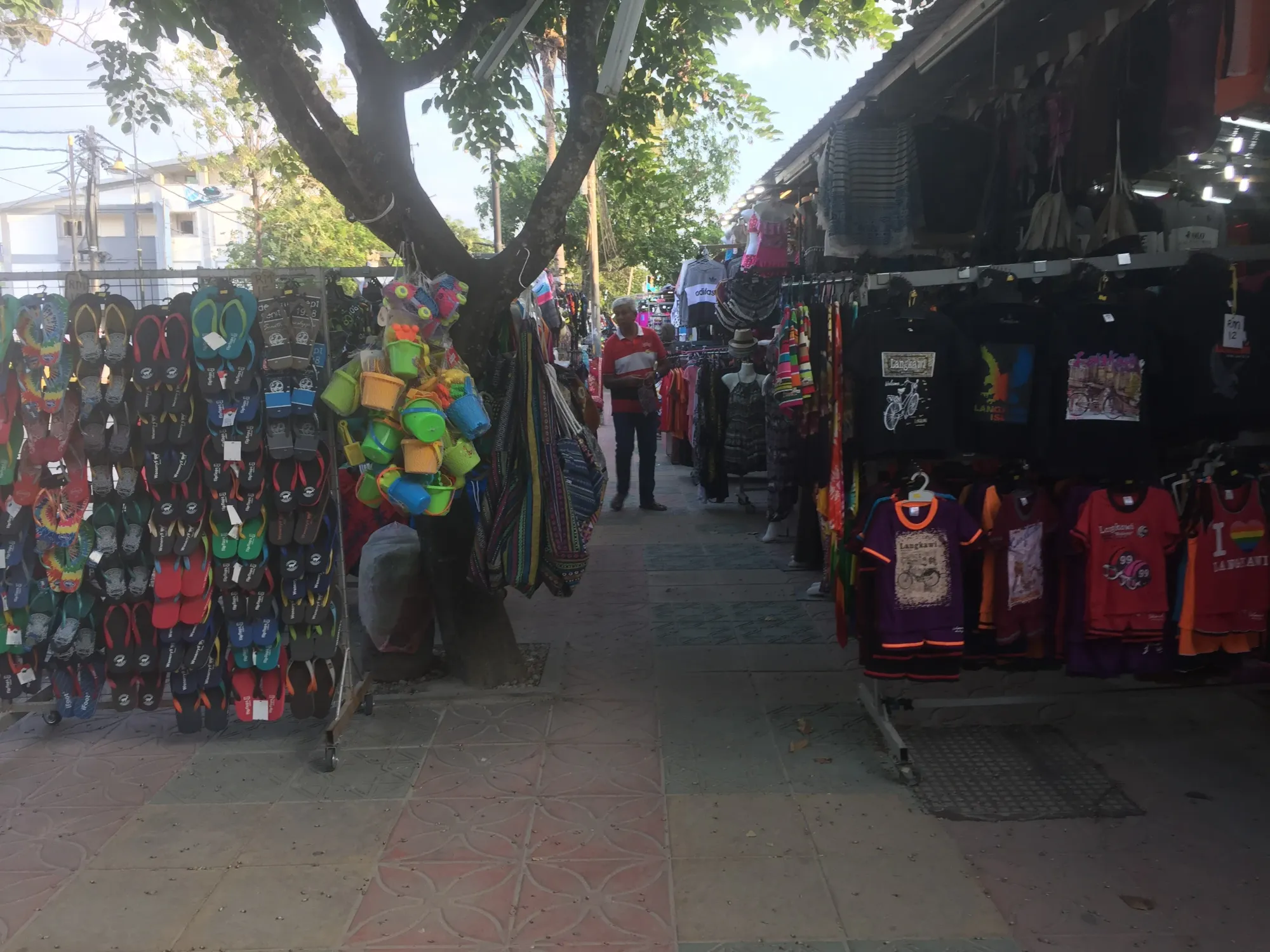 Street market stalls selling colorful sandals and clothing