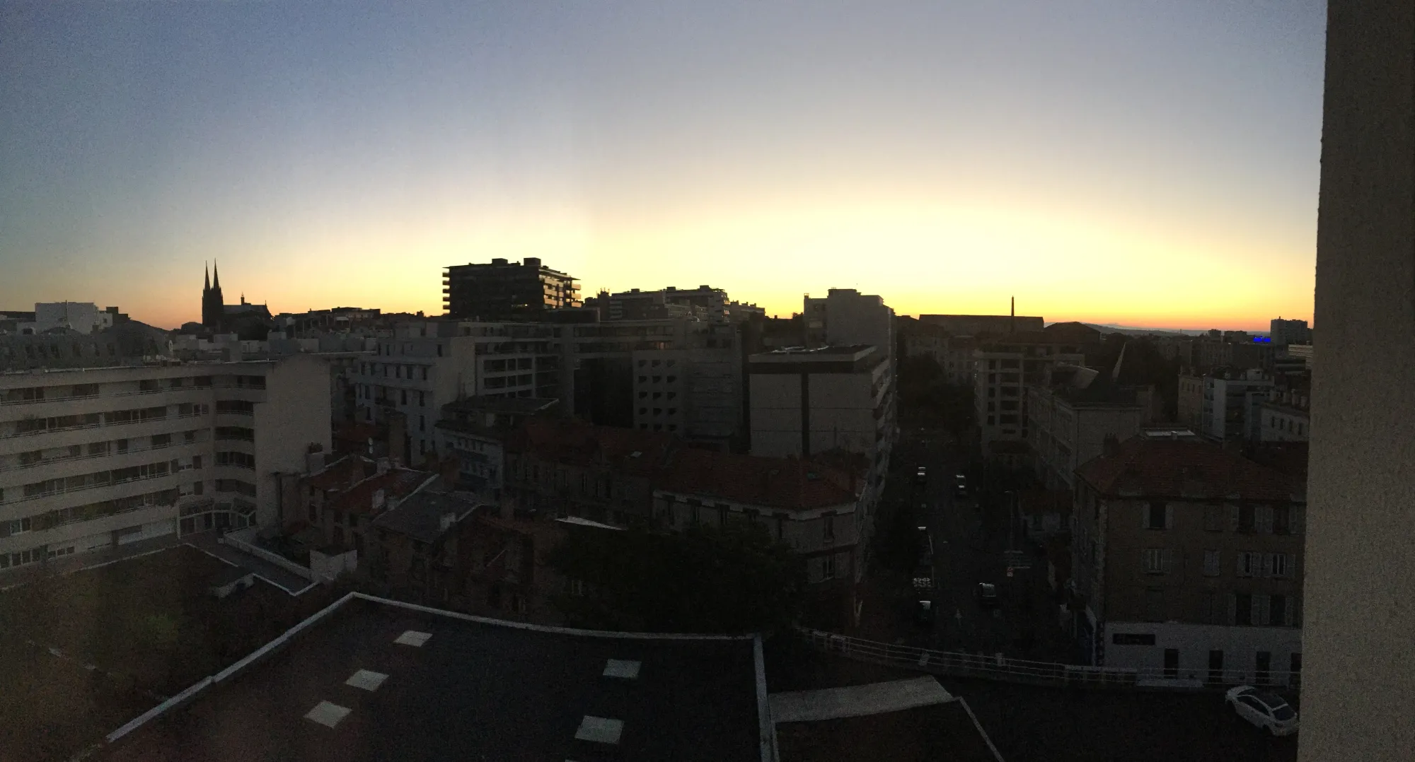 Panoramic dawn view over Clermont-Ferrand skyline with gothic cathedral spires silhouetted on the left