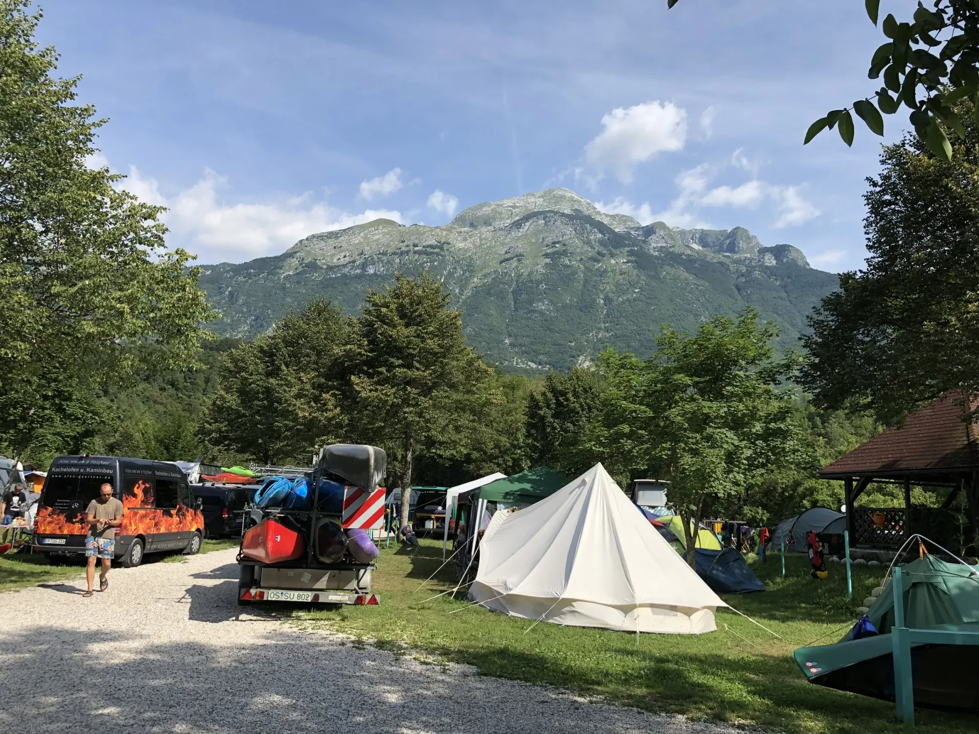 Mt Kanin above the campsite — tents, canoe trailers, alpine backdrop.