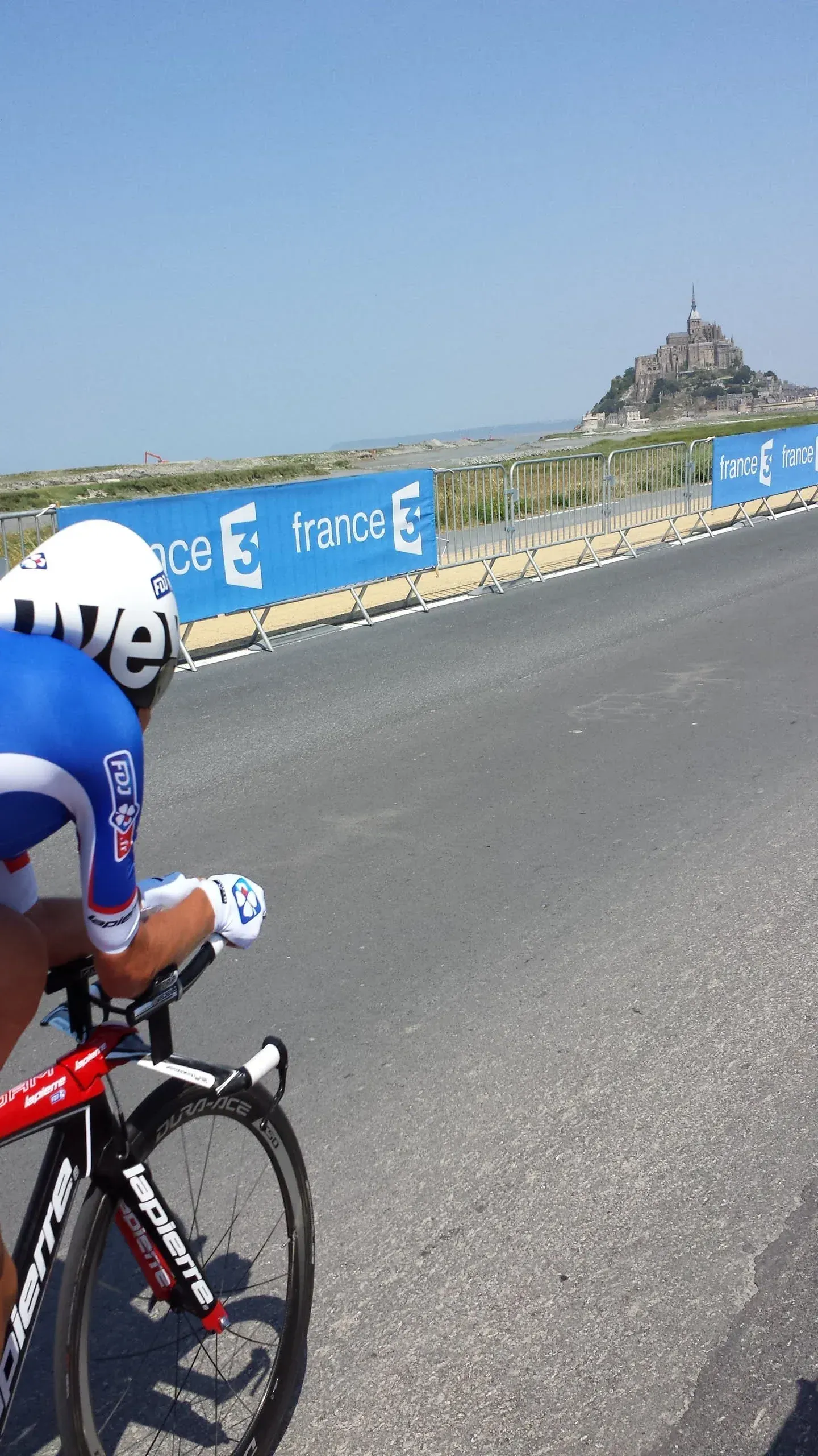 Cyclist on road with Mont Saint-Michel in distance