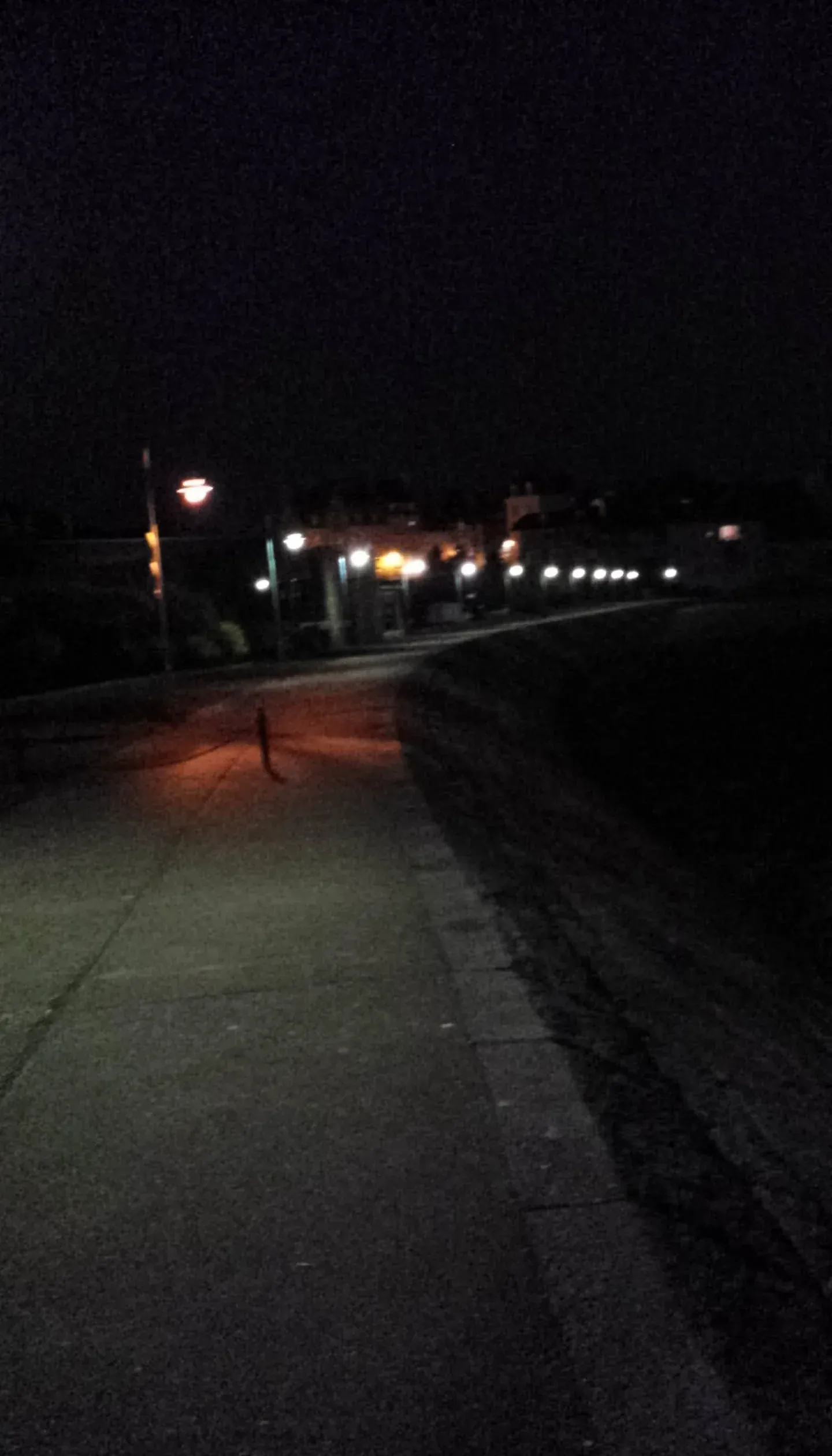 Night street with lit buildings and lone figure
