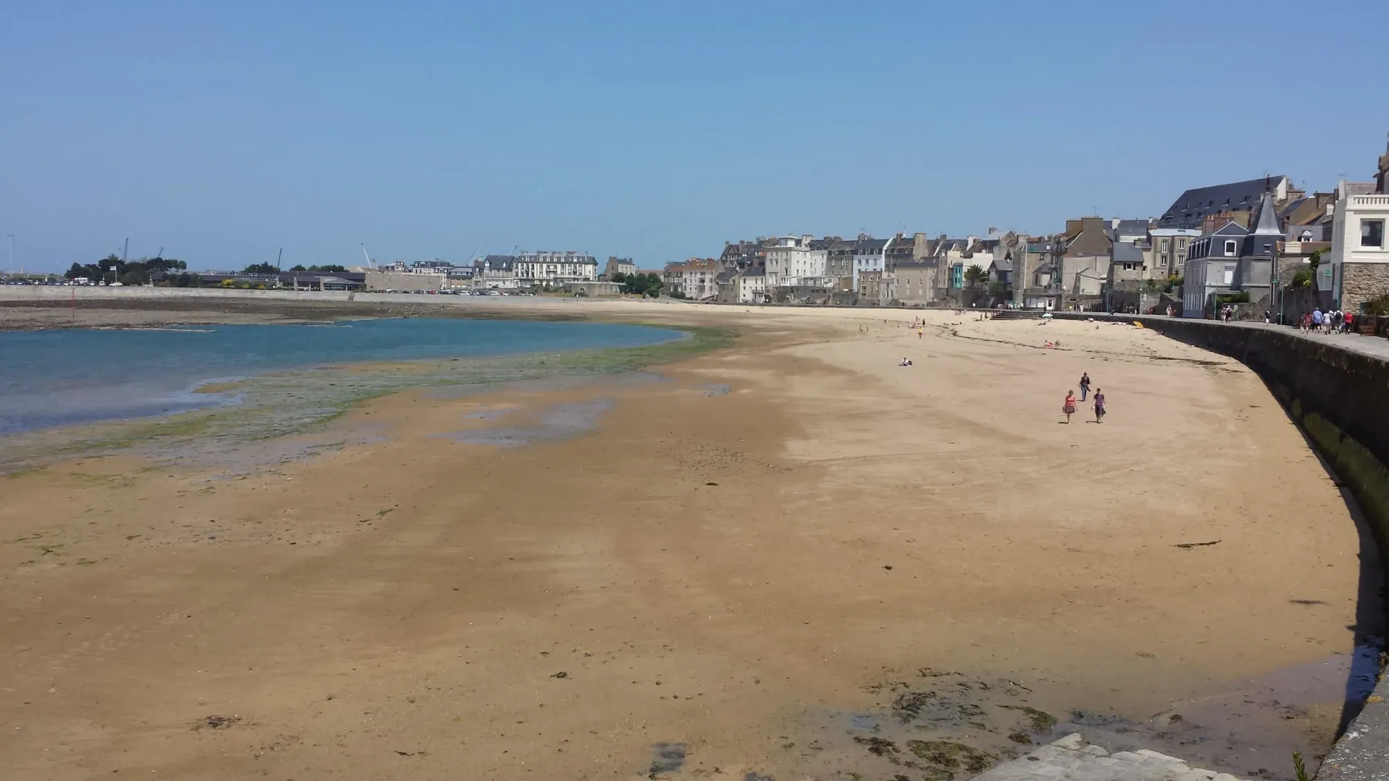 Sandy beach with stone buildings and tidal pools