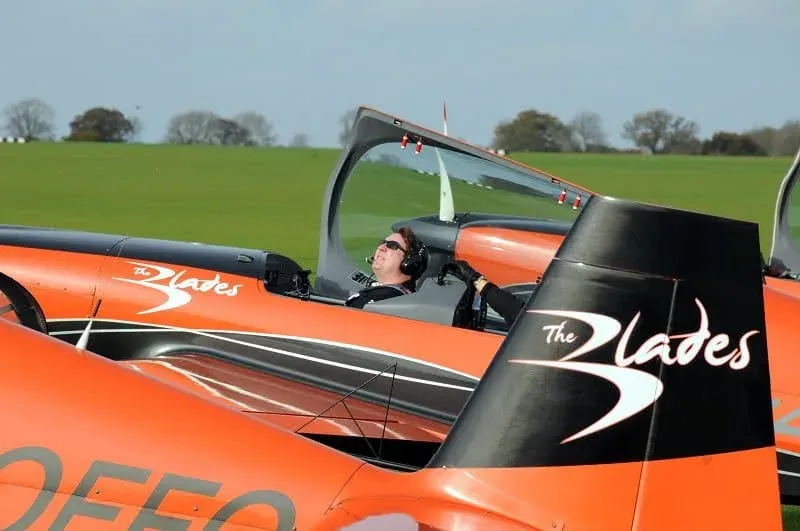 Pilot in cockpit of red Blades aerobatic aircraft in flight