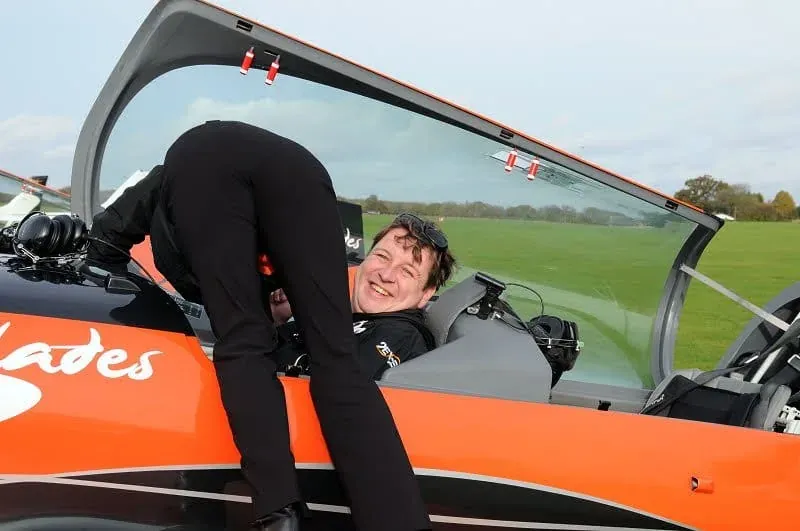Man sitting in red and black aerobatic aircraft cockpit
