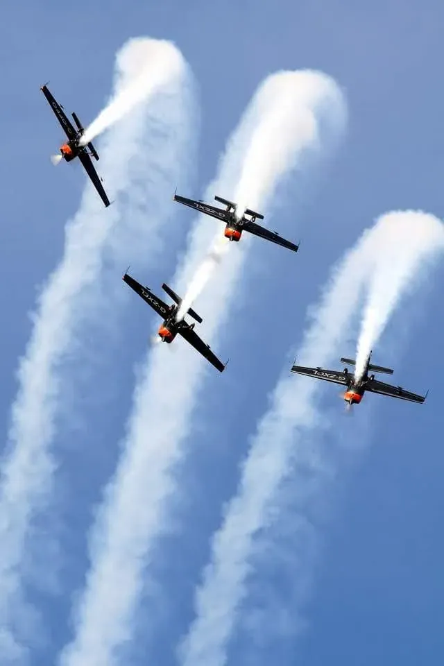 Four aerobatic aircraft in formation with smoke trails