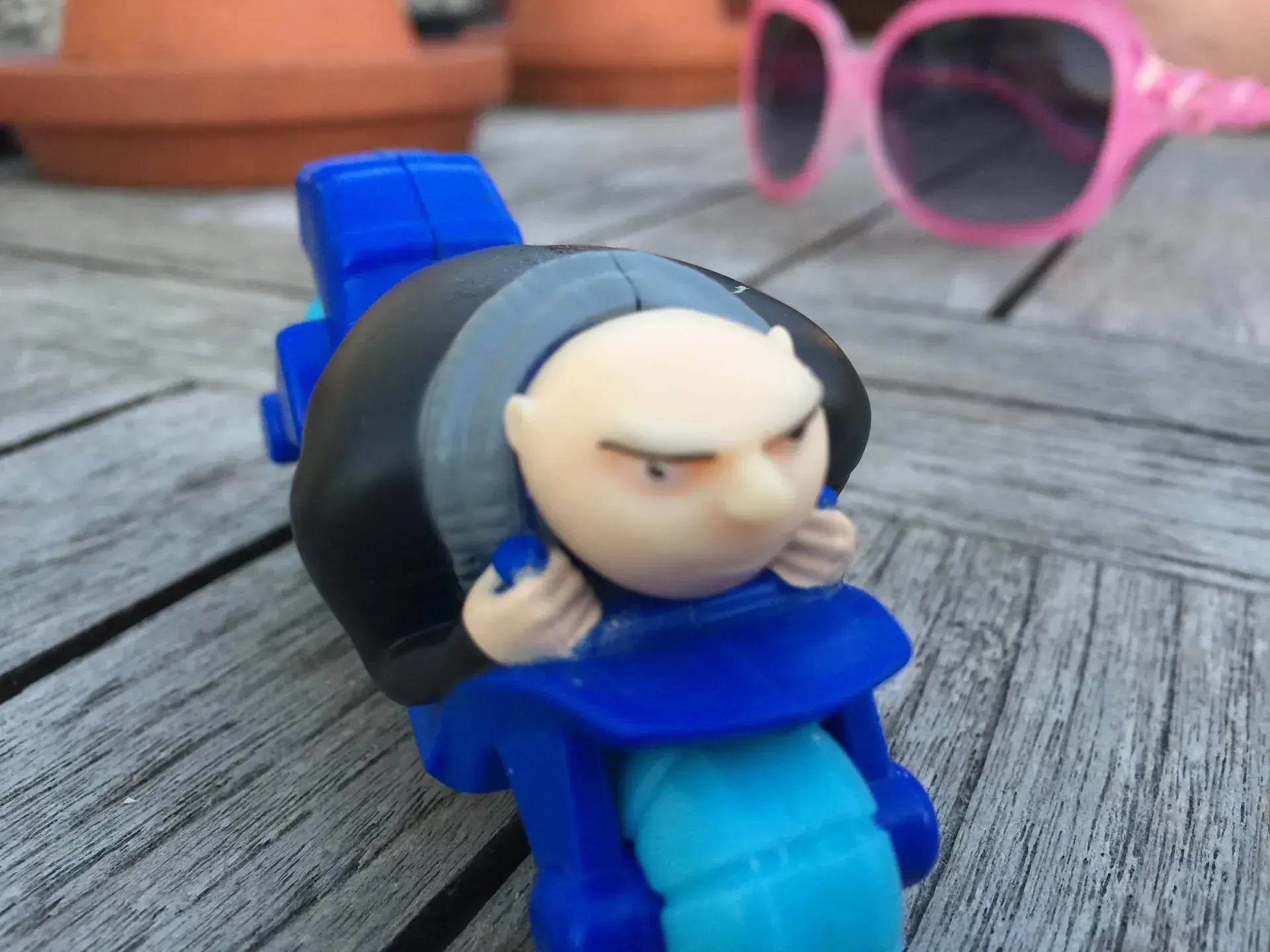 Toy figurine and pink sunglasses on wooden deck, Surbiton