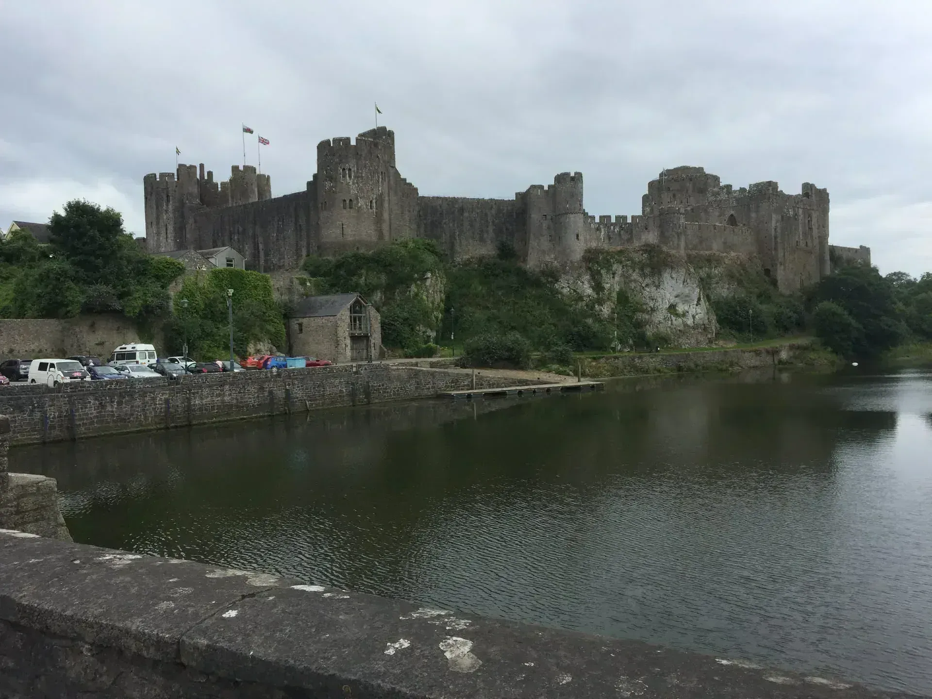 Medieval stone castle with multiple towers reflected in river water below