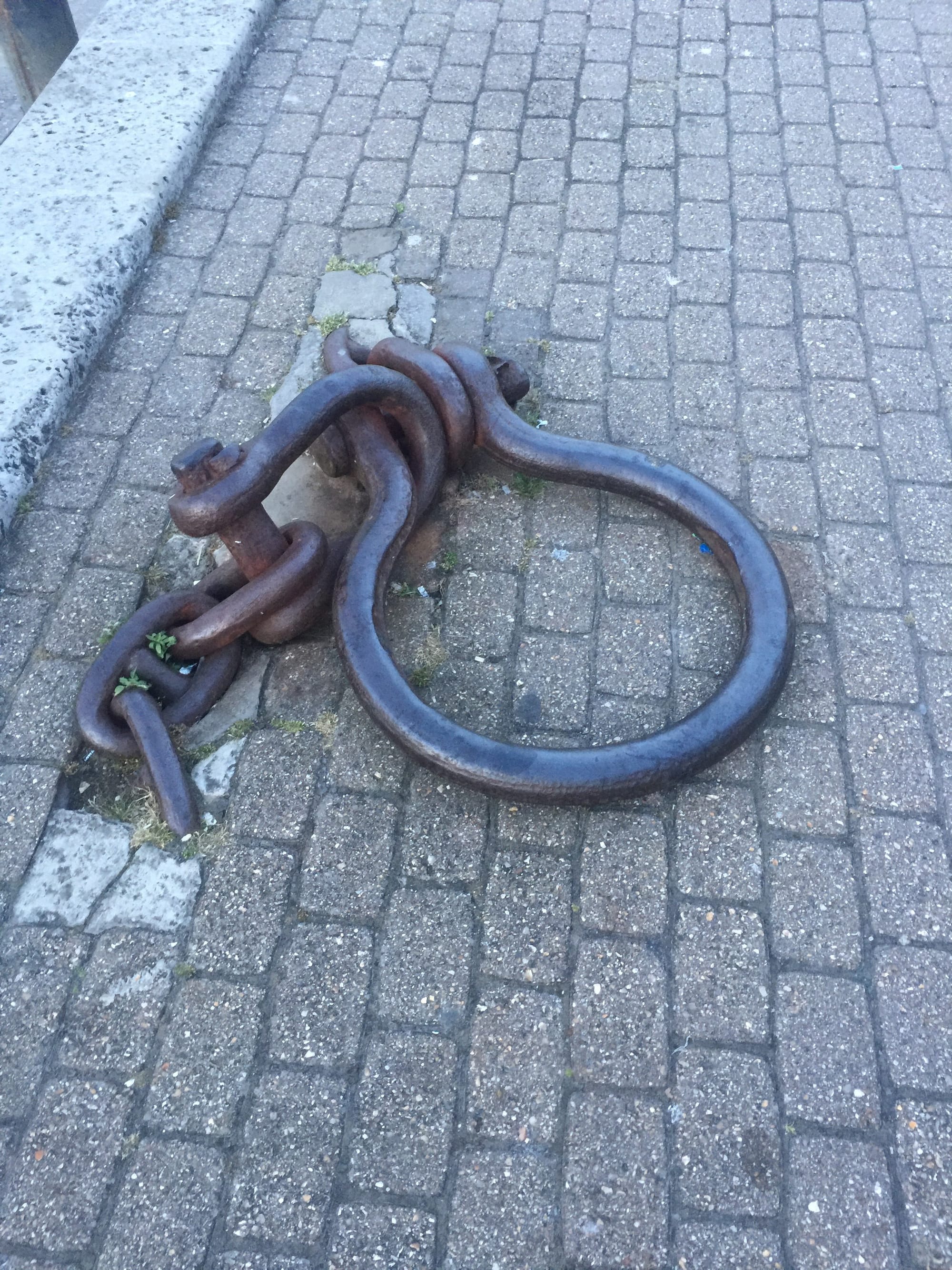 Rusted iron chain and ring on pavement, Rodwell