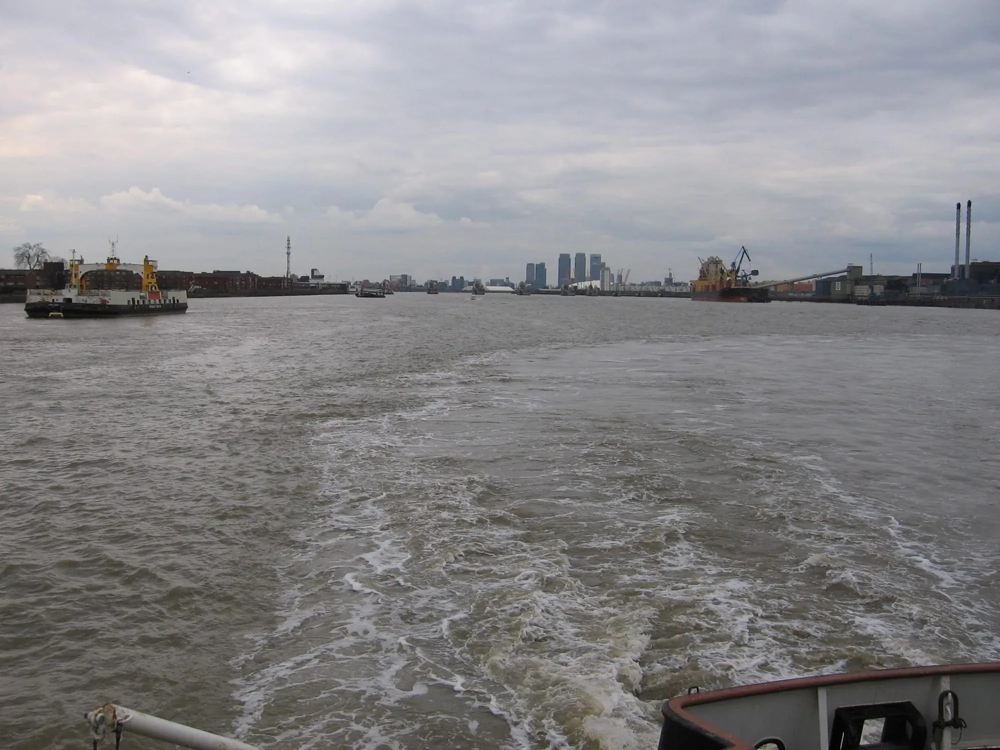 Thames river with moored vessels and London skyline across water from boat